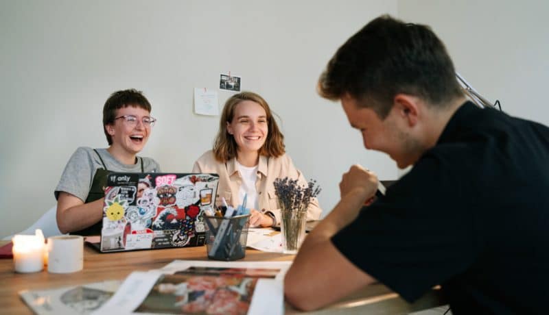 Trois collègues discutent et rigolent au bureau.