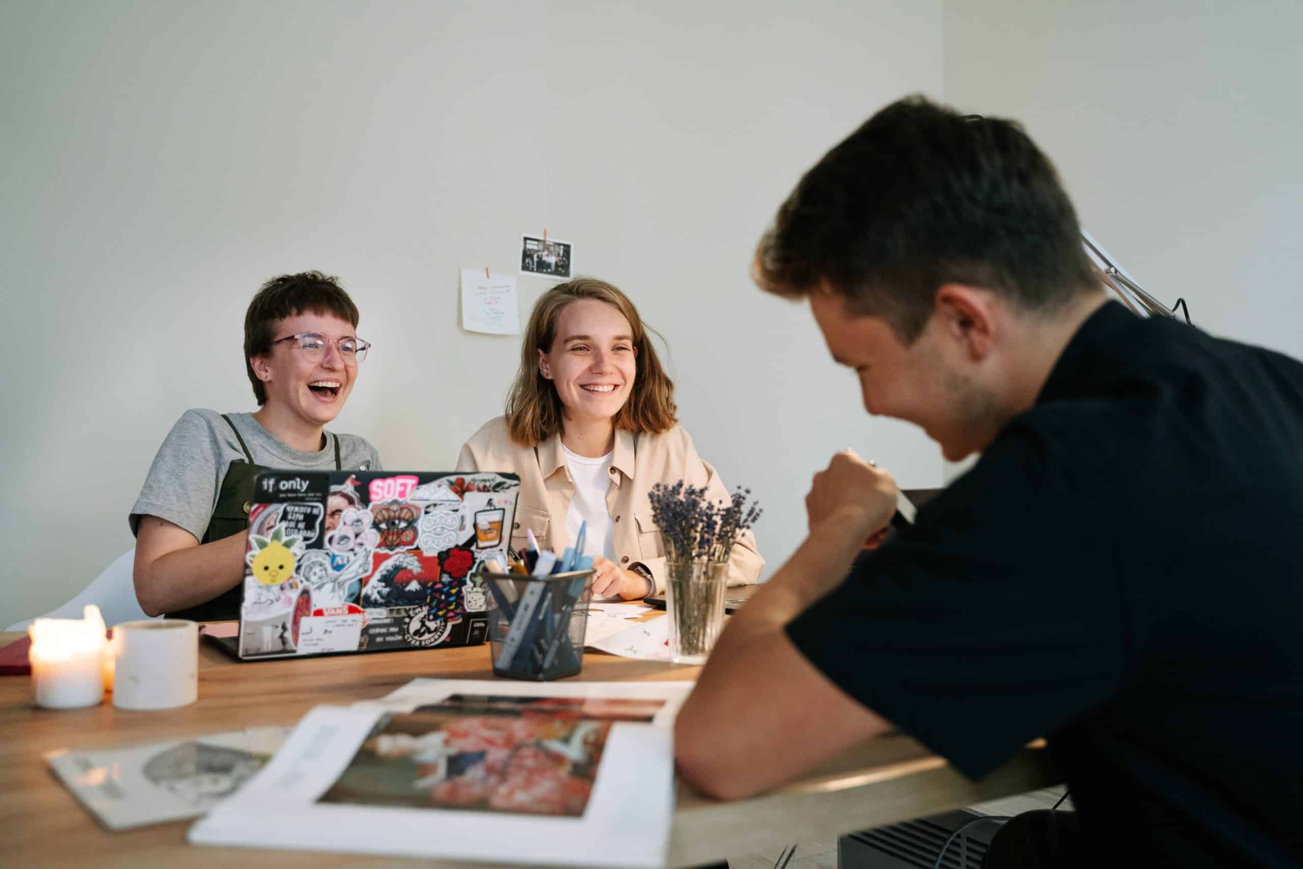 Trois collègues discutent et rigolent au bureau.